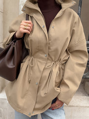 A mid-length coat with a stand-up collar and drawstring at the waist for women